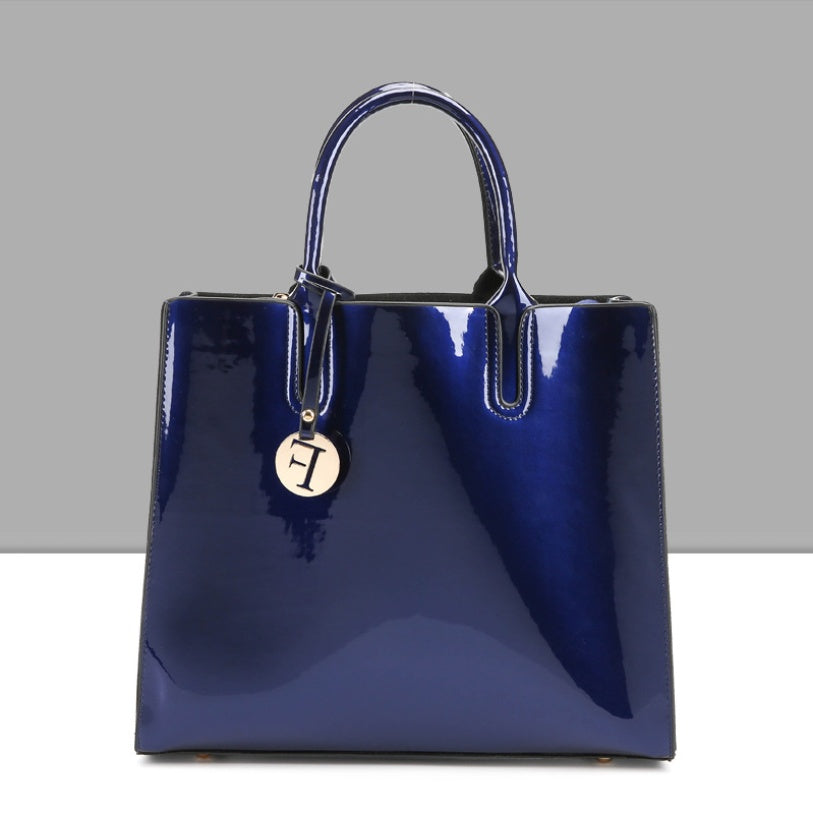 Blue glossy handbag with a gold tag on a gray background