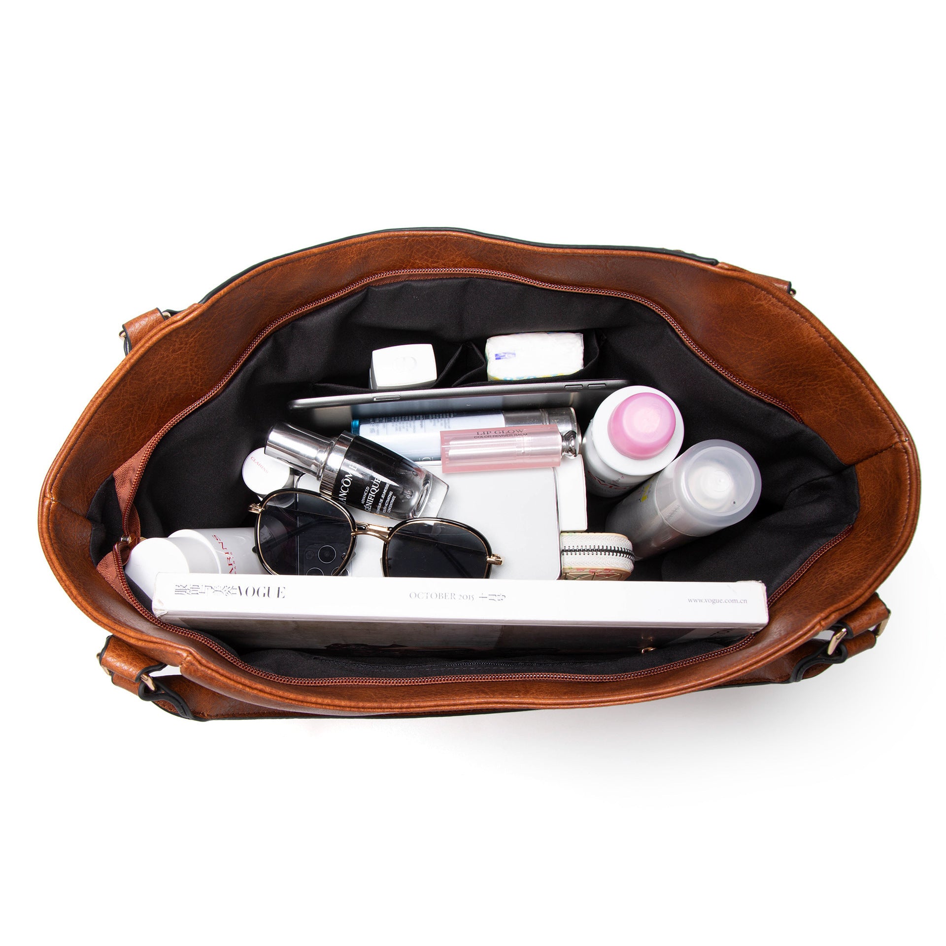 Brown leather handbag with cosmetic items on a white background