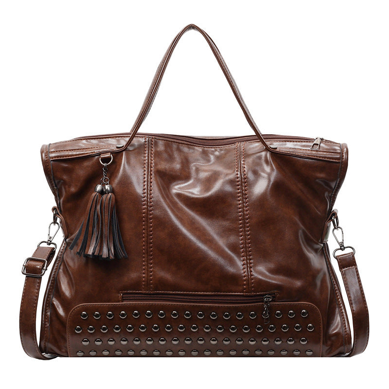 Brown leather handbag with studded detail and tassel on a white background
