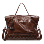 Brown leather handbag with studded detail and tassel on a white background