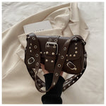 Brown leather handbag with studs held by a person on a light background