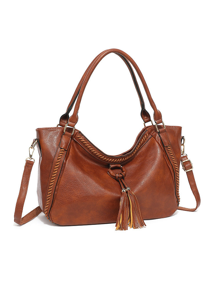 Brown leather handbag with tassel on a white background