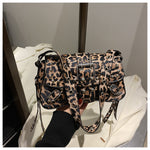 Leopard print handbag held by a person against a neutral background