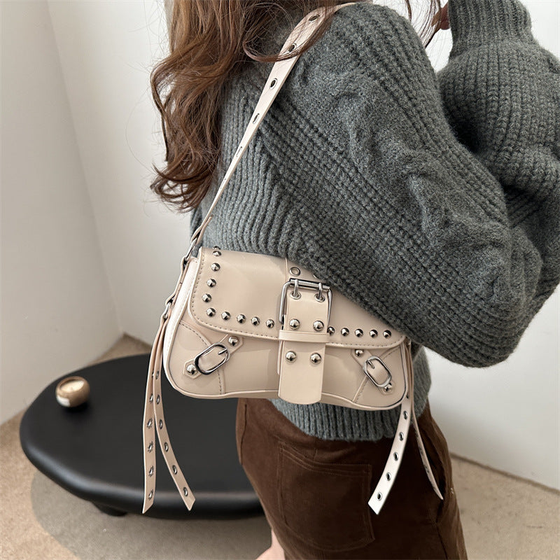 Person wearing a gray sweater with a beige studded handbag.