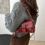 Person wearing a gray sweater with a red studded handbag.