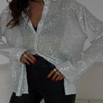Person wearing a silver sequin shirt with a neutral background