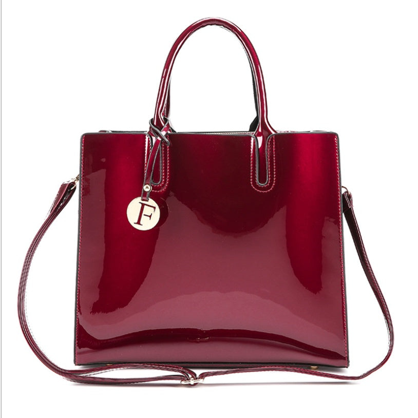 Shiny red handbag with a visible brand logo on a white background