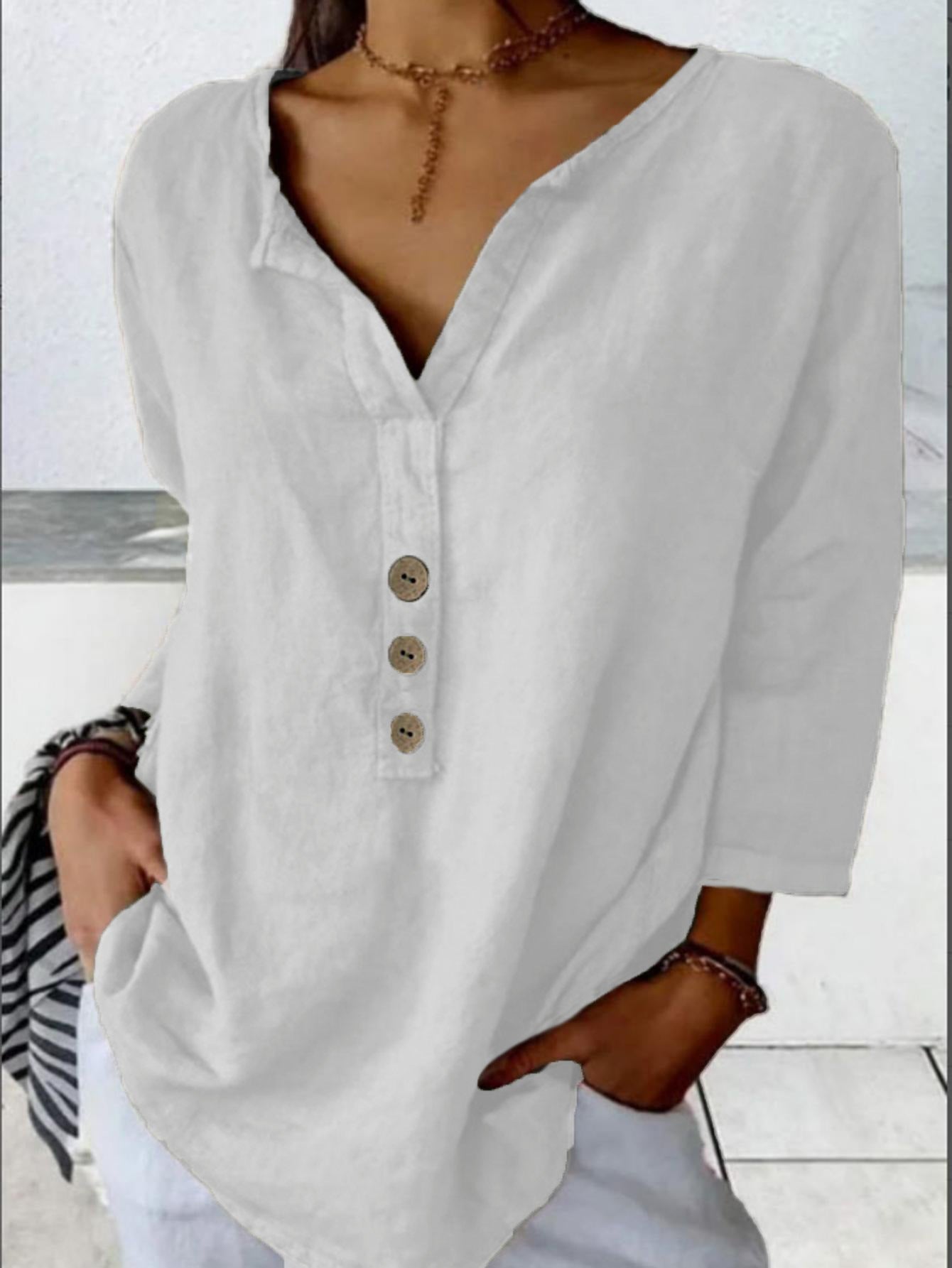White long-sleeve shirt with buttons worn by a person against 