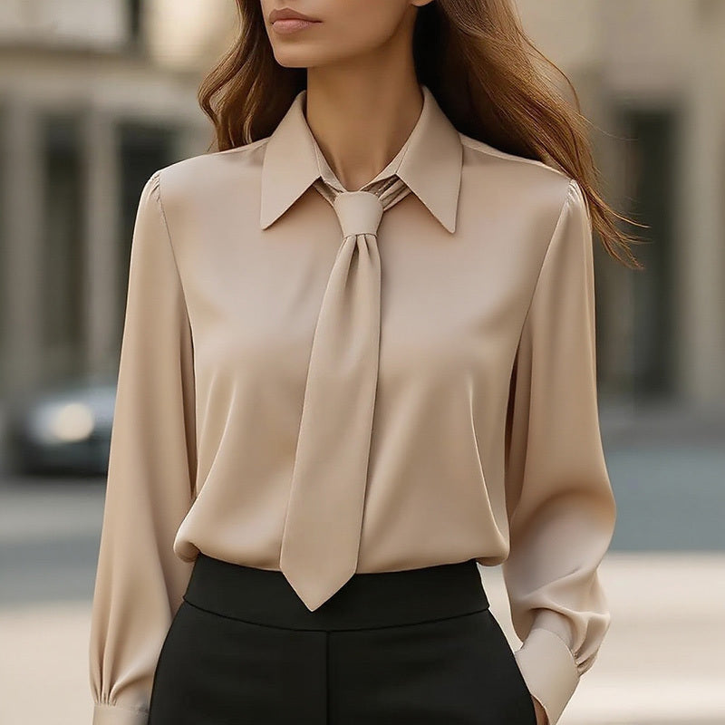Woman wearing a beige blouse with a tie detail in an urban setting