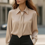 Woman wearing a beige blouse with a tie detail in an urban setting