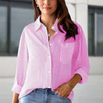 Woman wearing a pink and white striped shirt with a blurred background